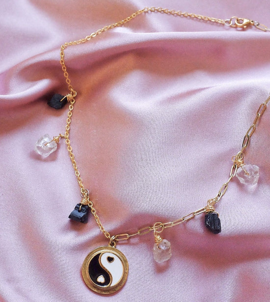 Gold choker necklace with half cable chain, half paper clip chain, and alternating black tourmaline and clear quartz mini crystals and a yin yang charm in the center
